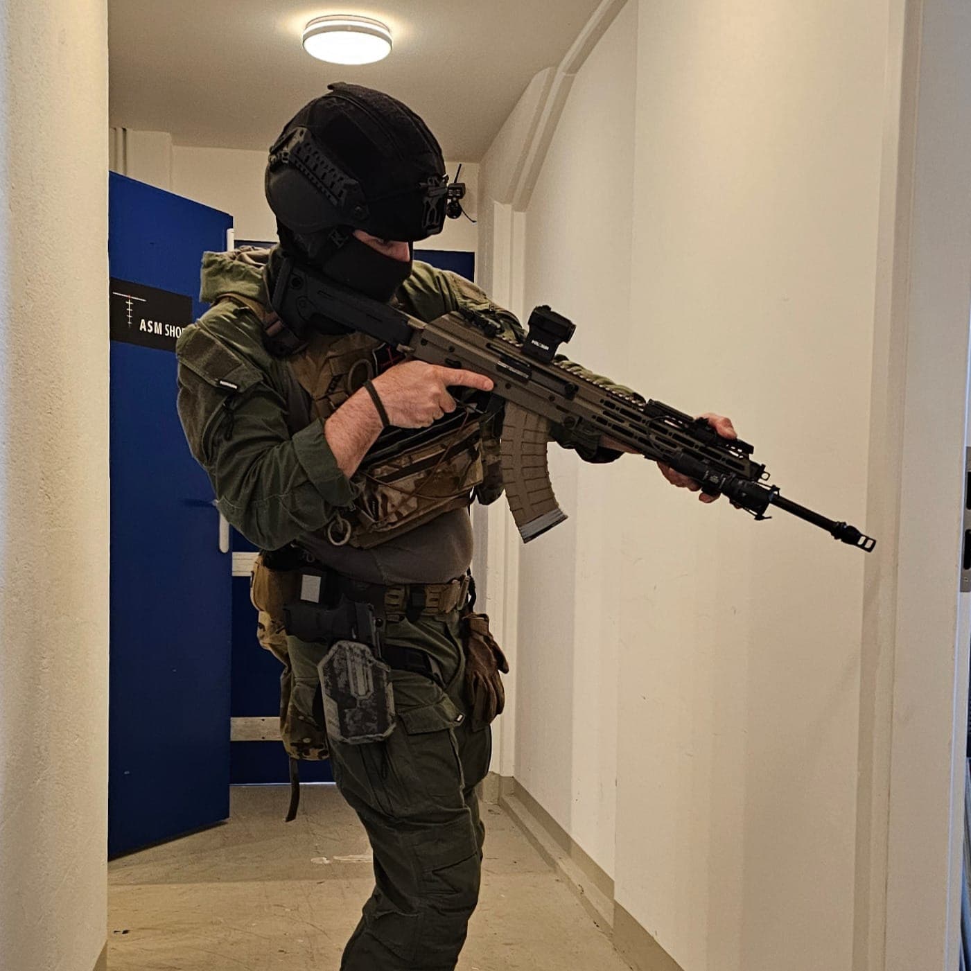Teilnehmer in voller Ausrüstung mit Gewehr in einem Korridor